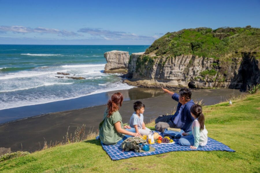 A family picnic at Muriwai Beach, Auckland traveling with kids in New Zealand